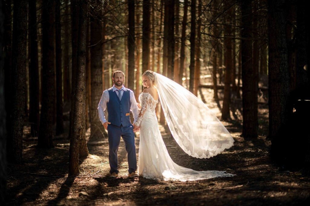 a sunshine coast bride and groom stand in a forest peppered with sunlight with sun shining on just them