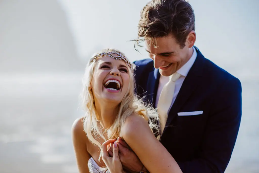 tofino adventure elopement and bride is laughing as groom cuddles her