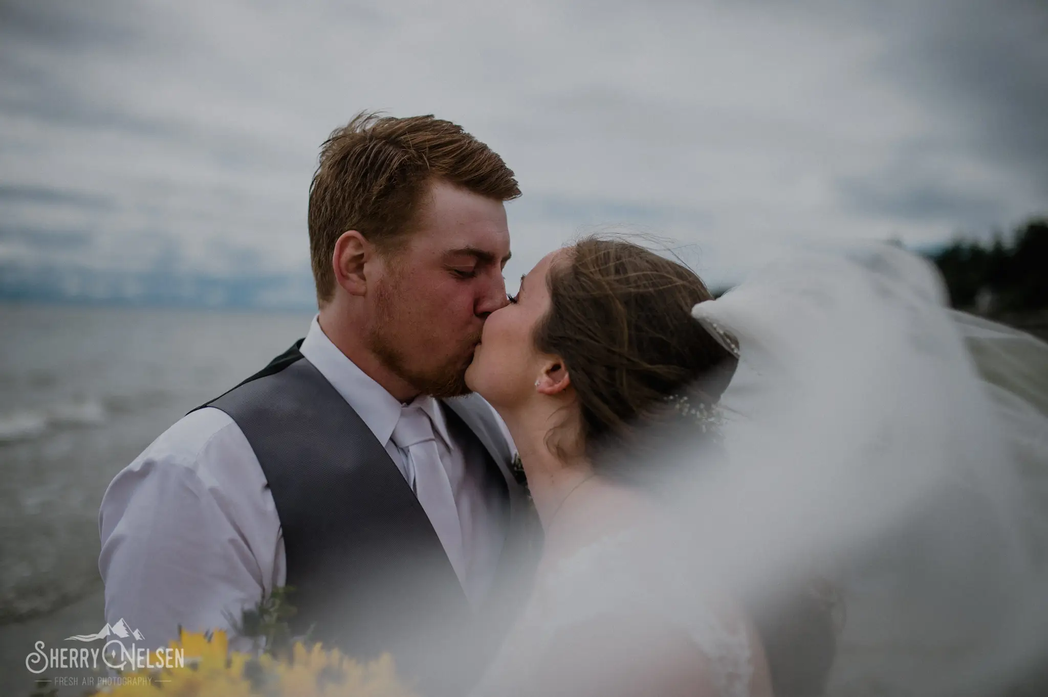 Shane and Shelbi's Sechelt wedding included a  kiss along the beach with her viel flying in the air