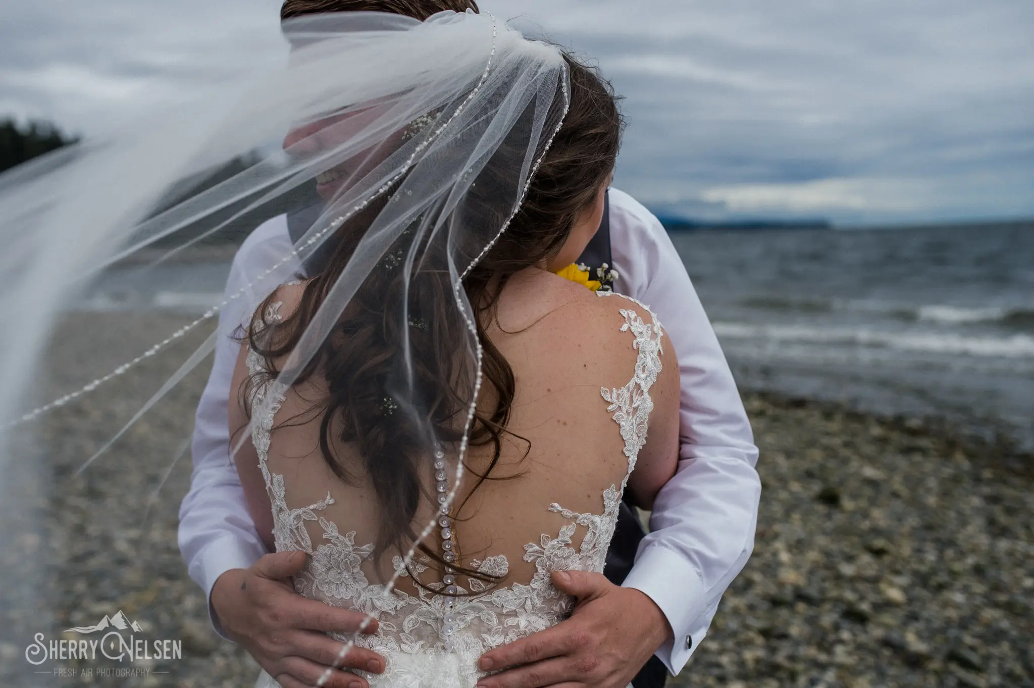 bride and groom embrace with her viel flying in the air for a Sechelt BC wedding