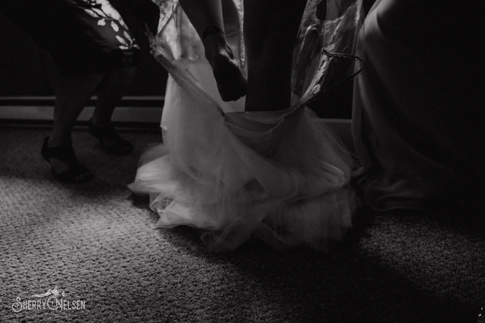 bride steps into the dress with the help of her mom and sister just before she walks down the aisle