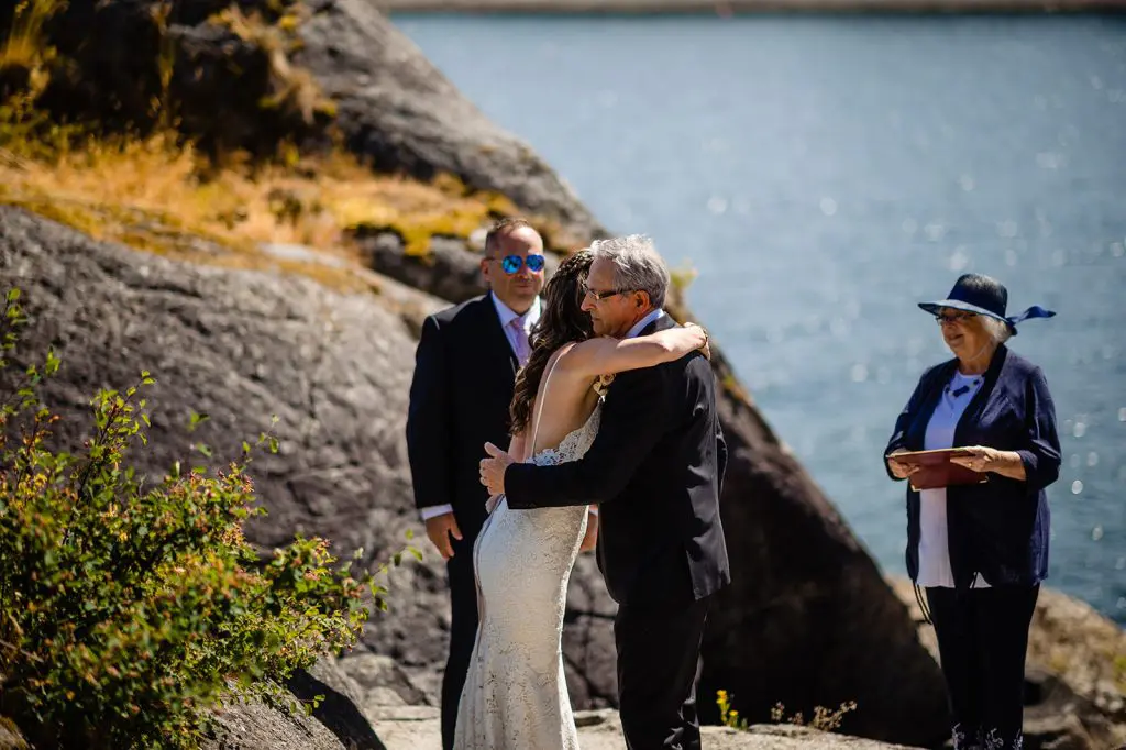 father hugs bride at the alter