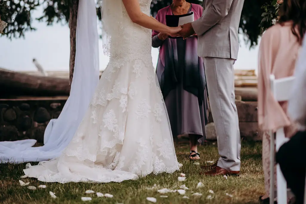 bride and groom clasp hands together as they marry