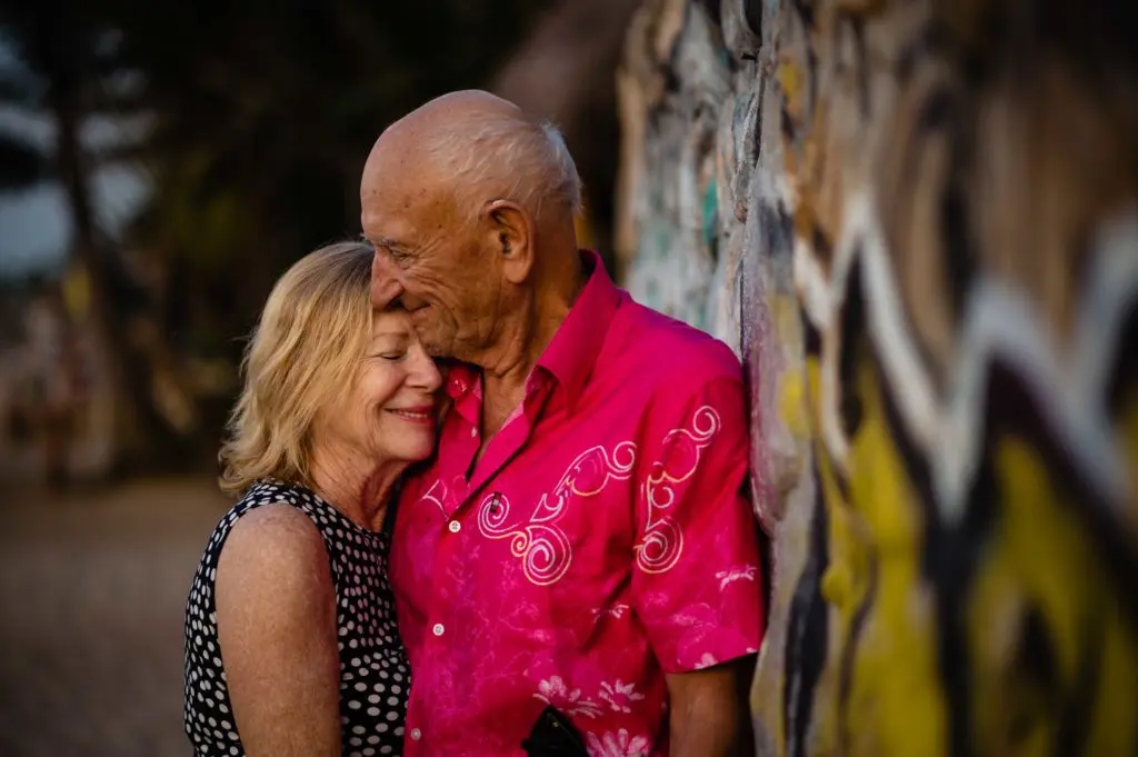 couple on the beach near a rock wall with graffiti have a quiet moment to reflect on their lives together