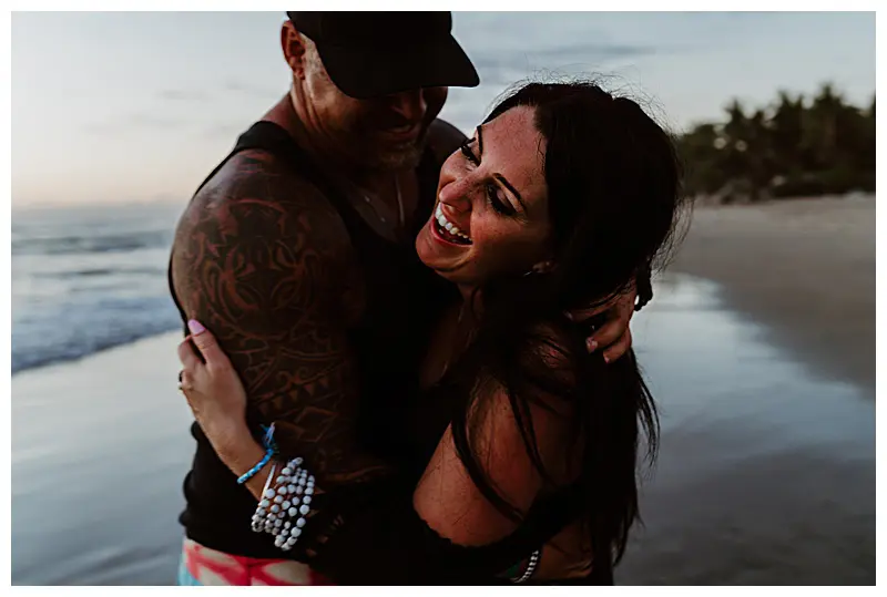 couple laughing in embrace at a beach sunset photo session Mexico