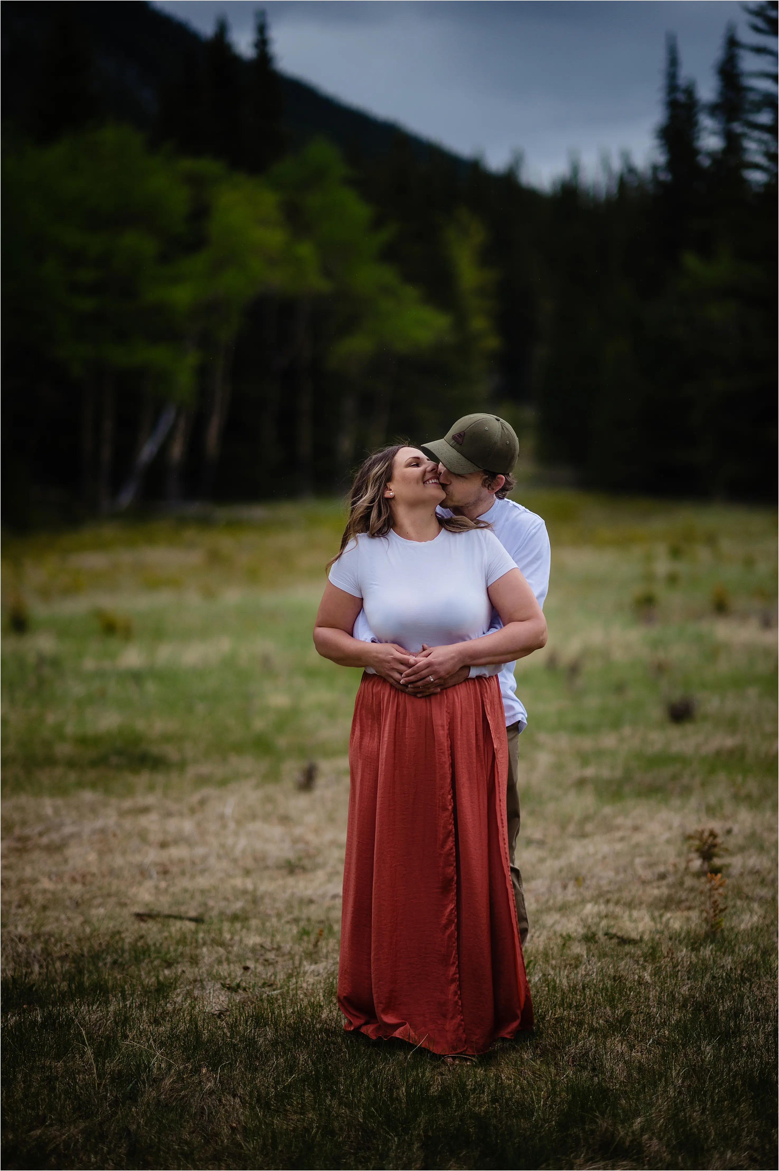 Tim embraces and kisses Yvonne from behind at their Banff engagement photo session