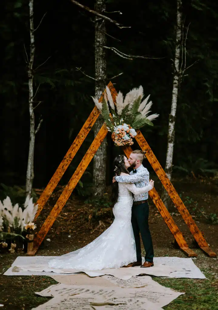 a bride and groom kiss at the end of their sunshine coast bc wedding in a forest near the ocean in sechelt